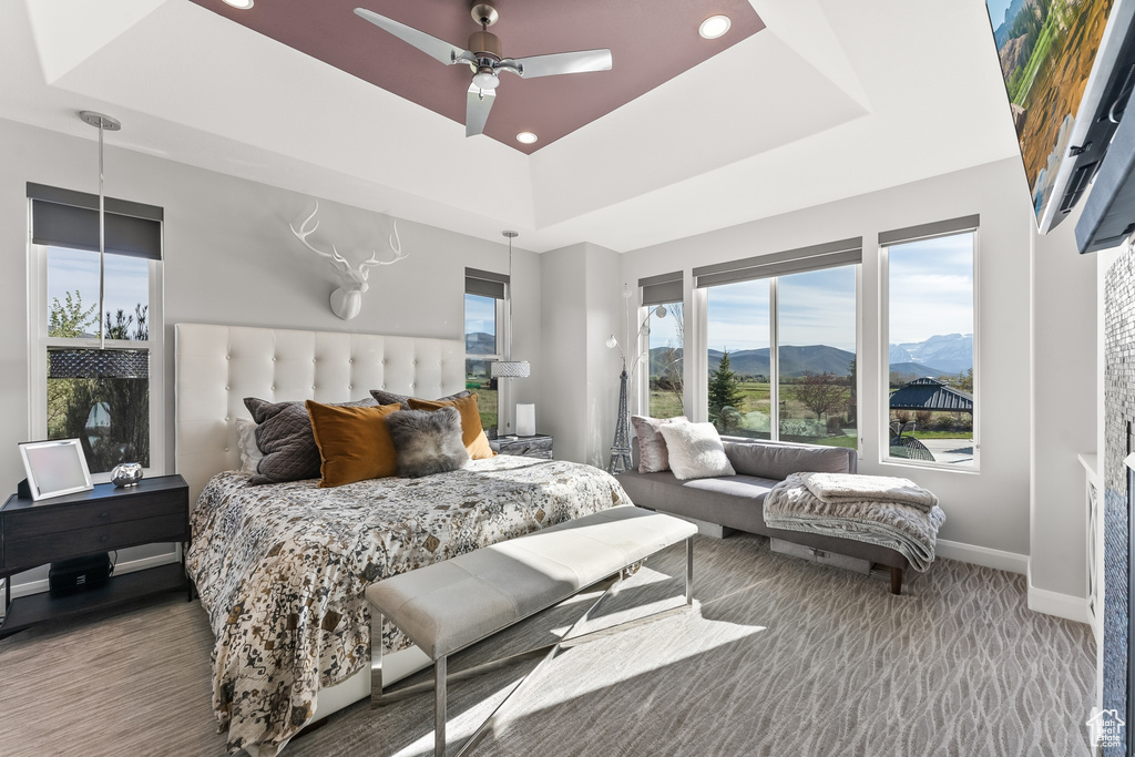 Bedroom featuring a mountain view, ceiling fan, a raised ceiling, and multiple windows