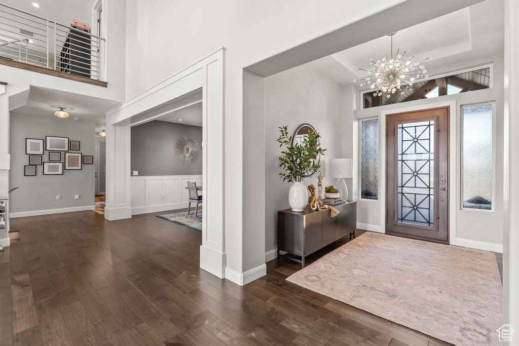 Foyer entrance featuring an inviting chandelier, dark hardwood / wood-style flooring, and a towering ceiling