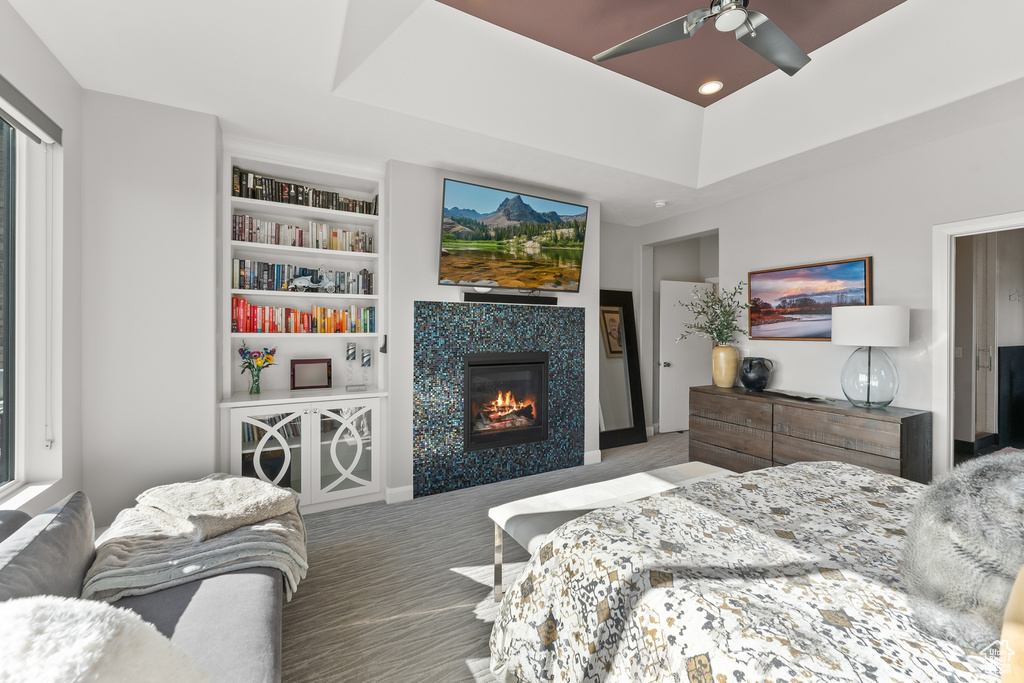 Bedroom with a fireplace, ceiling fan, and a tray ceiling