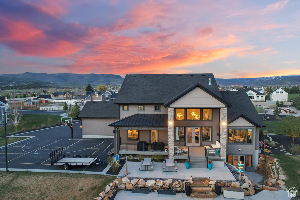 Back house at dusk with a patio, an outdoor living space, and a mountain view
