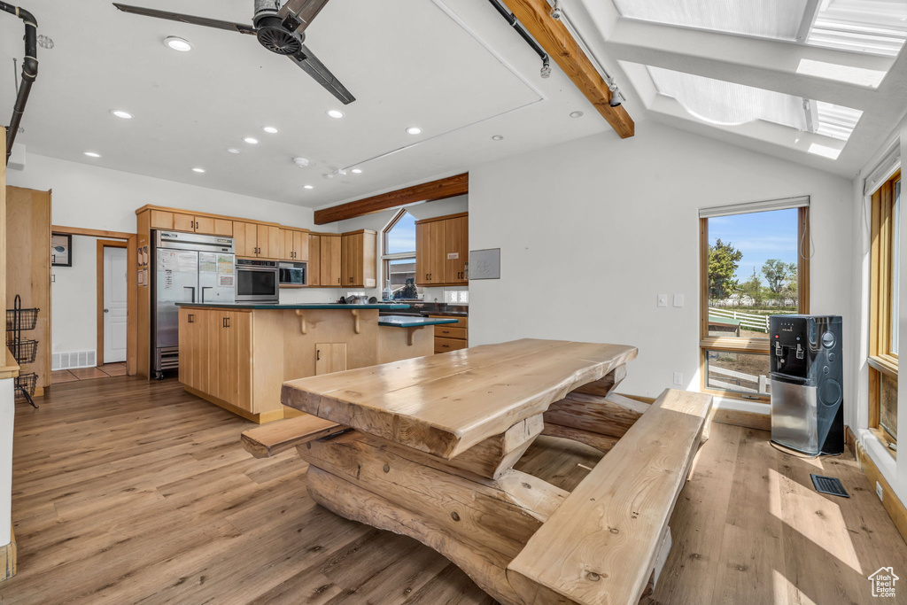 Dining area featuring lofted ceiling with skylight, light hardwood / wood-style flooring, and ceiling fan