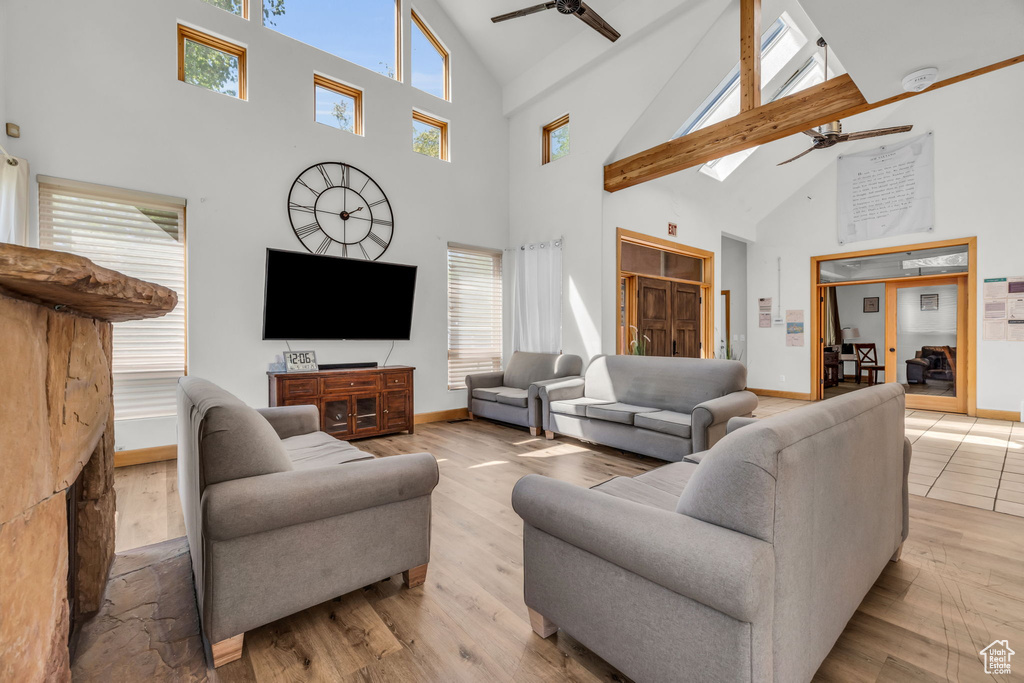 Living room with a wealth of natural light, high vaulted ceiling, ceiling fan, and hardwood / wood-style flooring