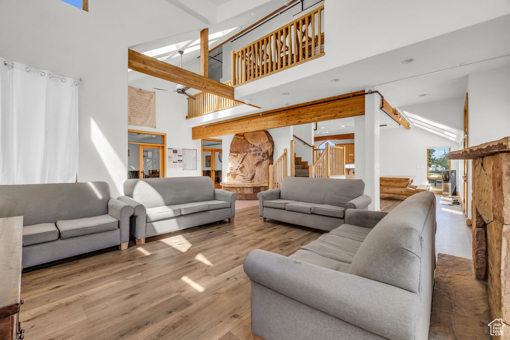 Living room featuring high vaulted ceiling, wood-type flooring, ceiling fan, and beam ceiling