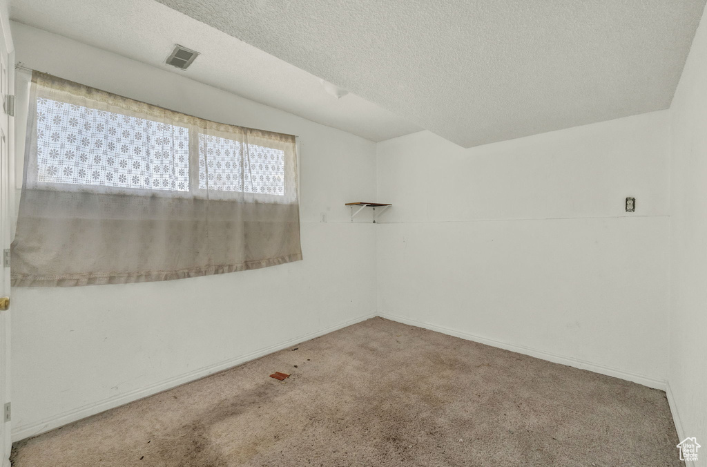 Empty room with a textured ceiling and carpet