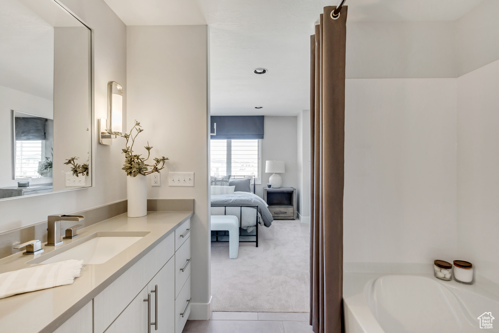 Bathroom featuring tile flooring, vanity, and a tub