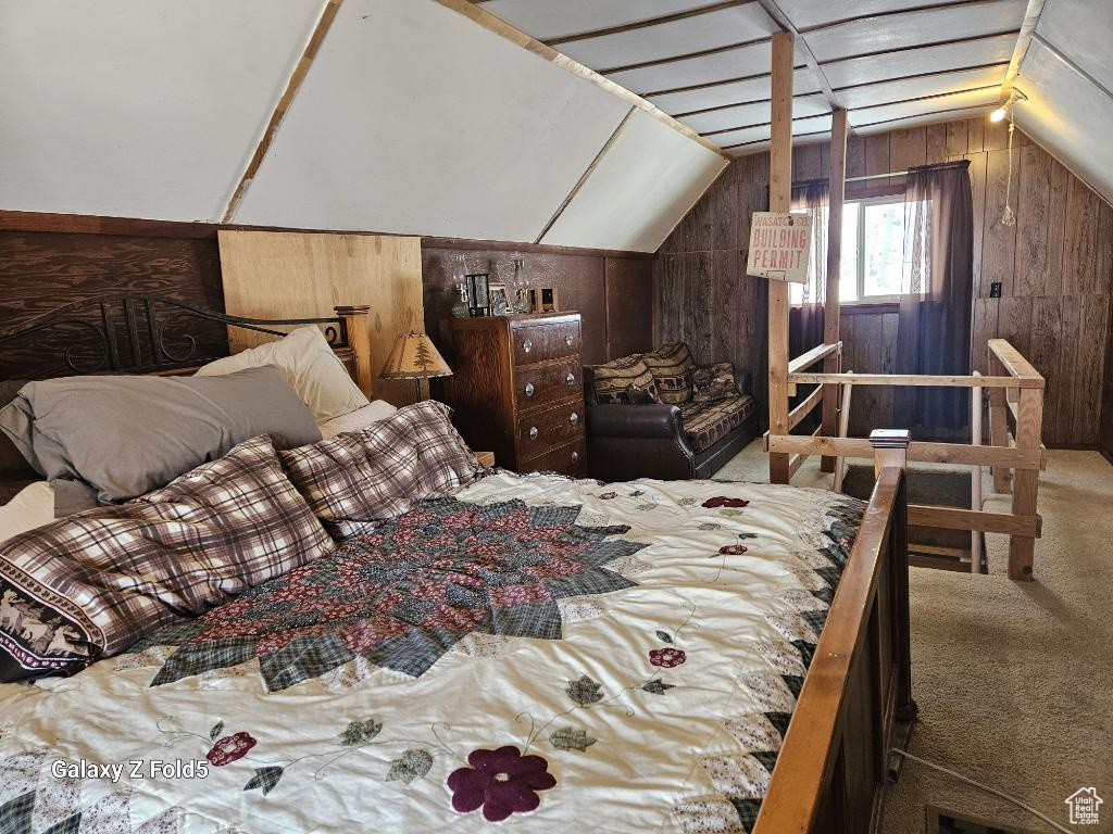 Bedroom featuring lofted ceiling, wood walls, and carpet flooring