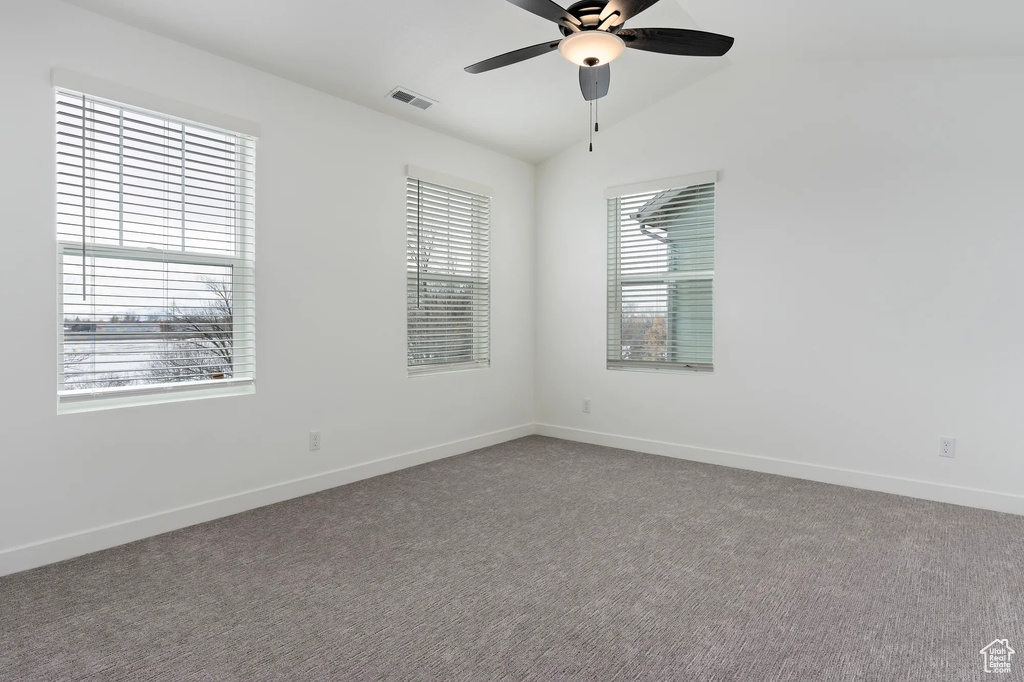 Carpeted empty room featuring vaulted ceiling and ceiling fan