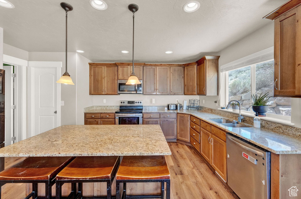 Kitchen with a center island, pendant lighting, stainless steel appliances, and sink