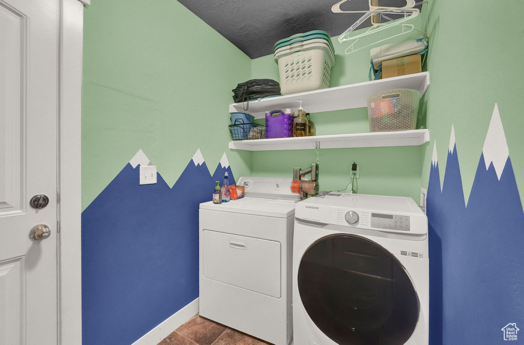 Clothes washing area with dark tile floors and independent washer and dryer