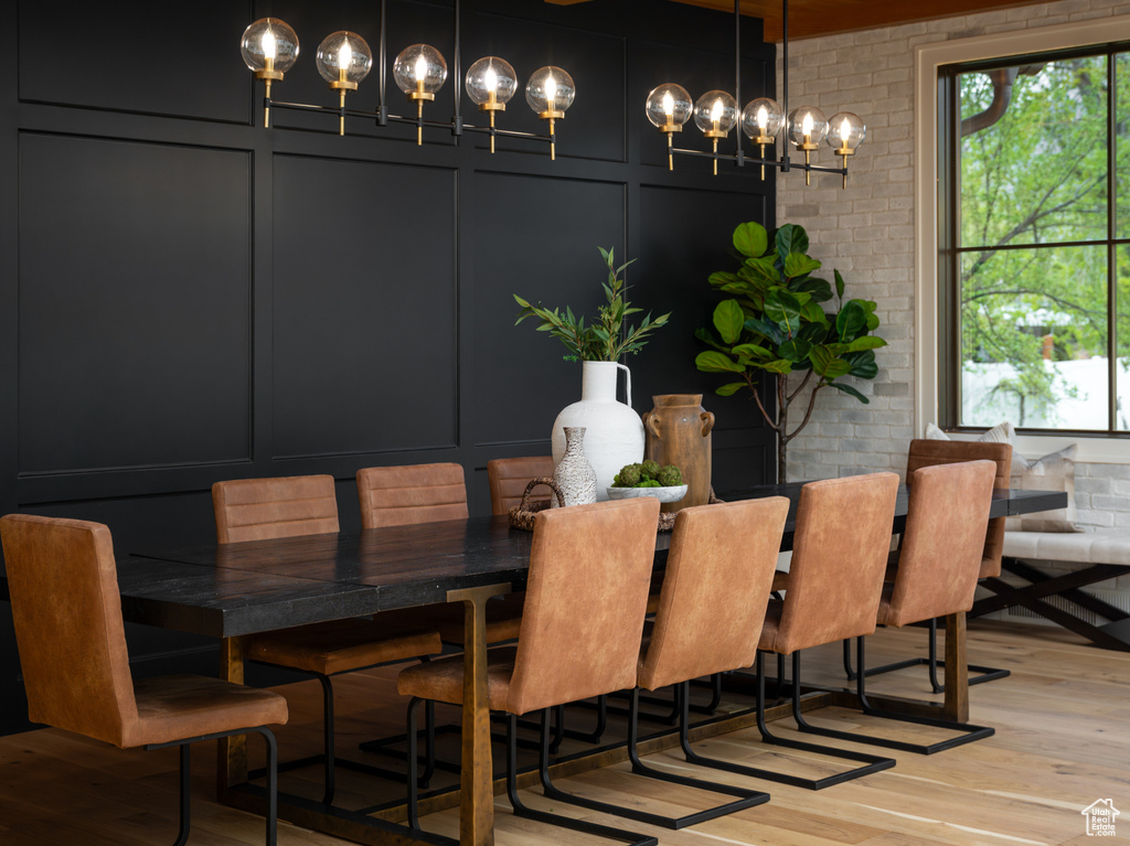 Dining space with light hardwood / wood-style flooring, a notable chandelier, and brick wall