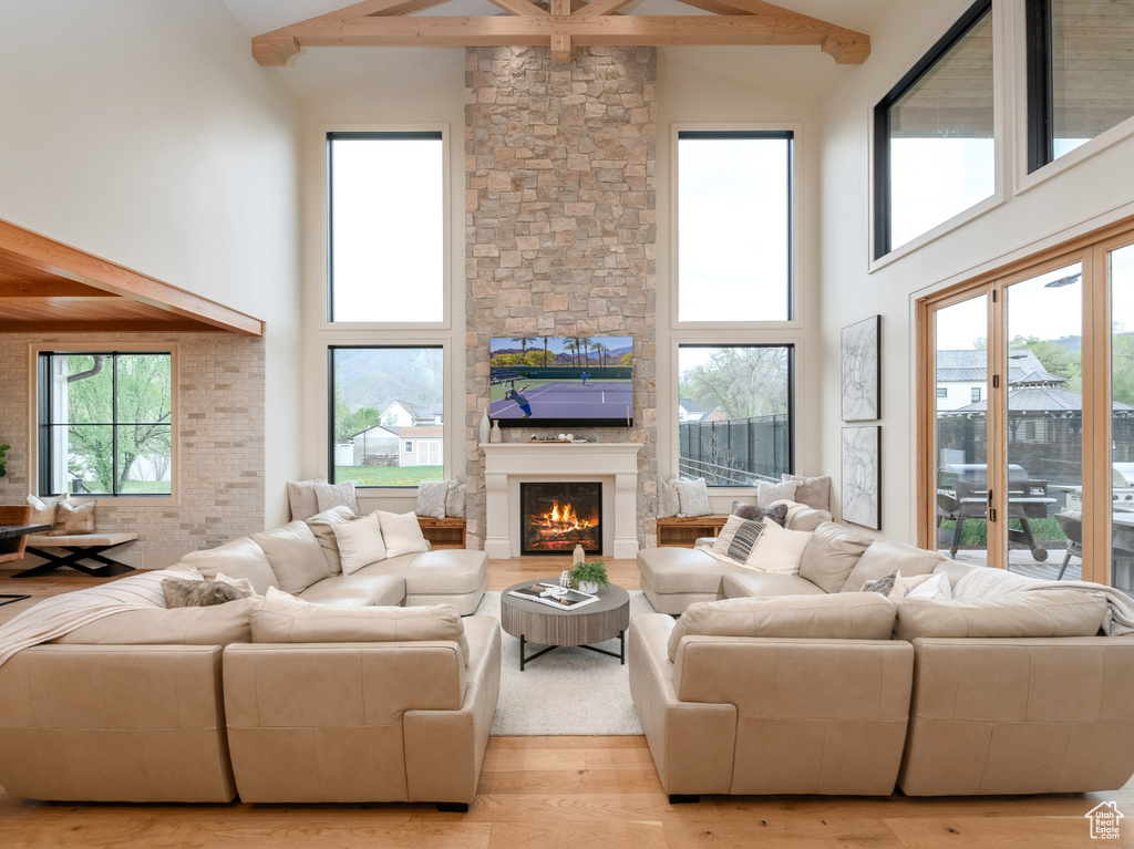 Living room featuring beam ceiling, high vaulted ceiling, hardwood / wood-style floors, and a fireplace