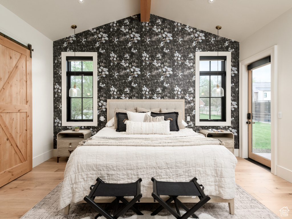 Bedroom with light hardwood / wood-style floors, vaulted ceiling with beams, access to exterior, and a barn door