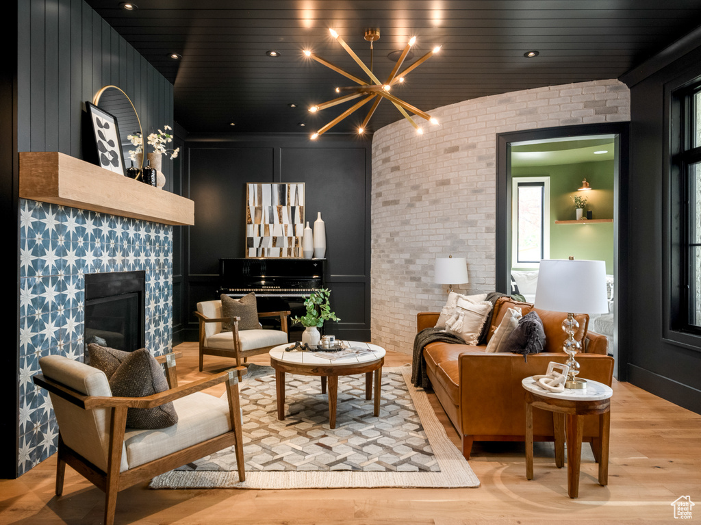 Living room with light hardwood / wood-style flooring, an inviting chandelier, and brick wall