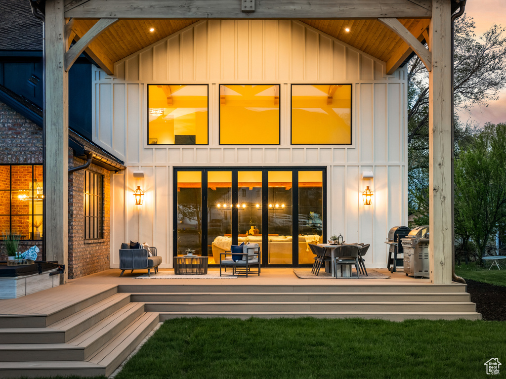 Back house at dusk featuring a patio, a yard, and a deck