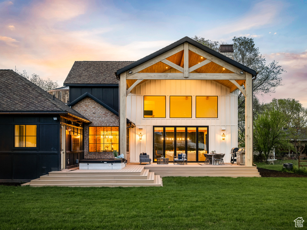 Back house at dusk featuring a patio and a yard