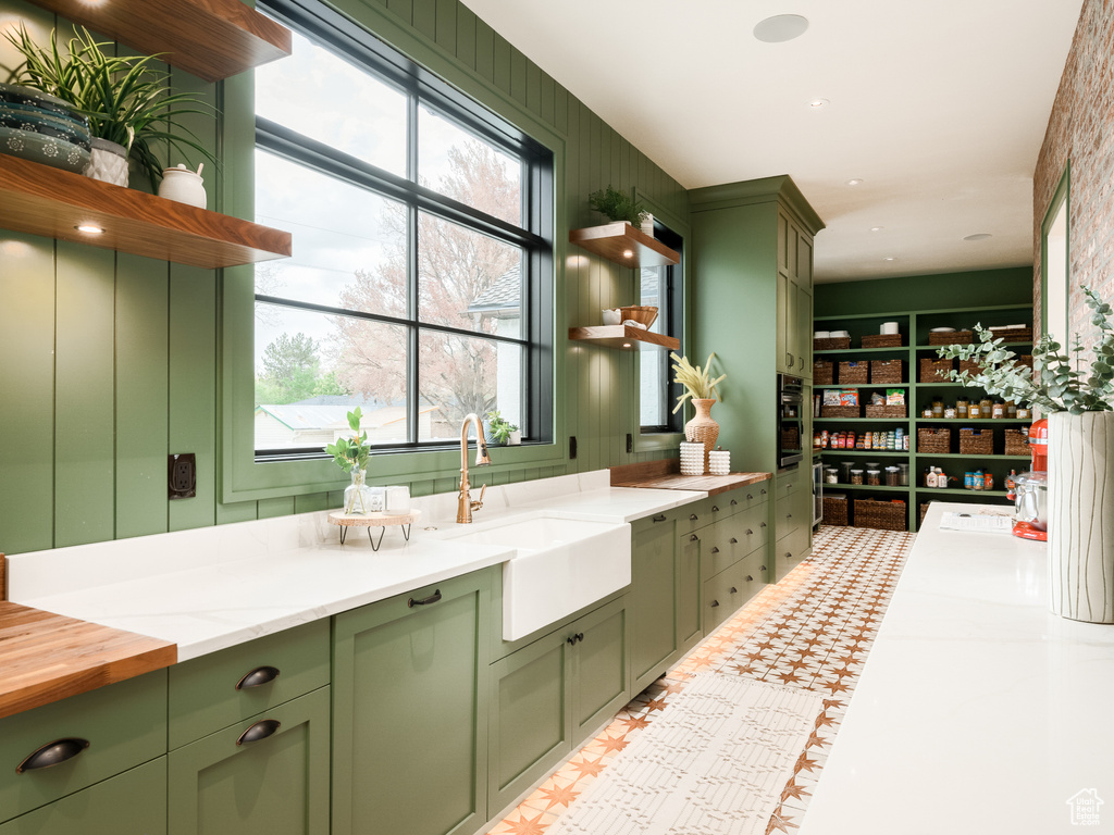 Kitchen featuring a wealth of natural light, green cabinets, and sink