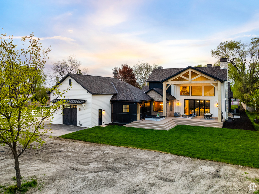 Back house at dusk featuring a yard