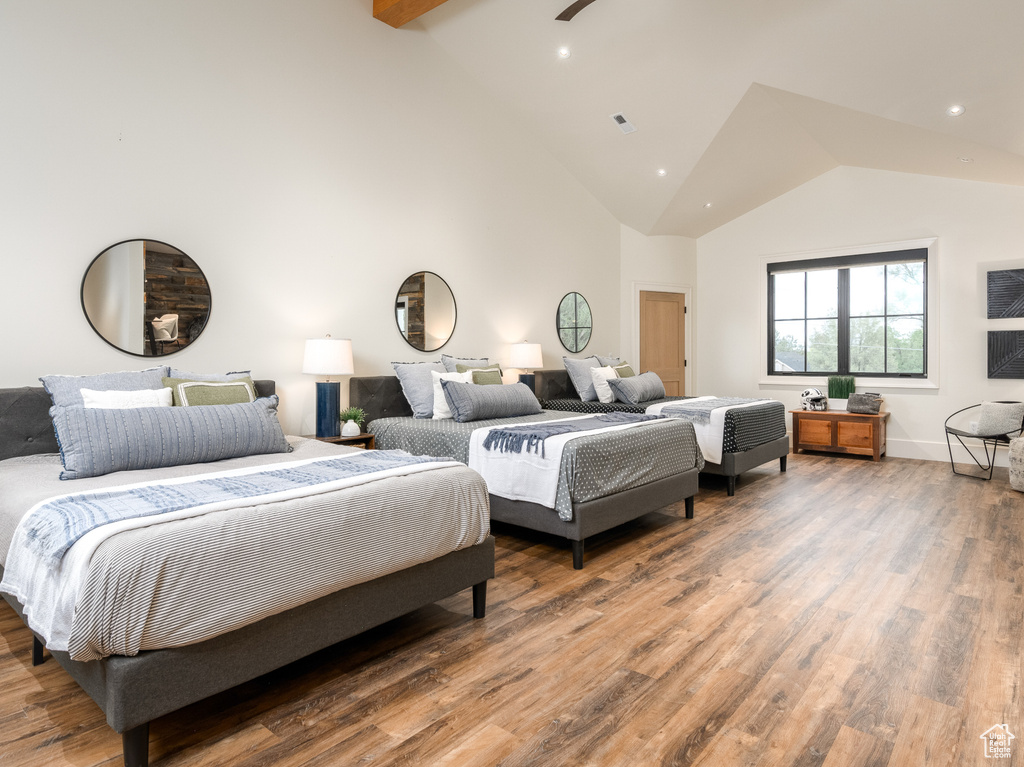 Bedroom with high vaulted ceiling, ceiling fan, hardwood / wood-style flooring, and beam ceiling