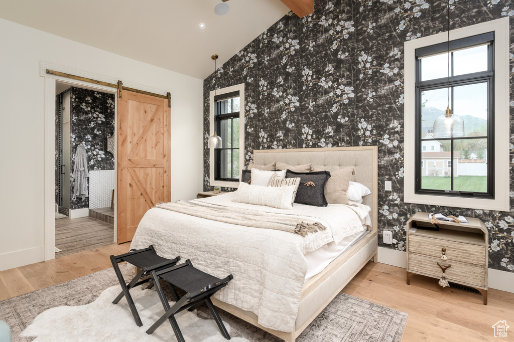 Bedroom with a barn door, hardwood / wood-style floors, and multiple windows