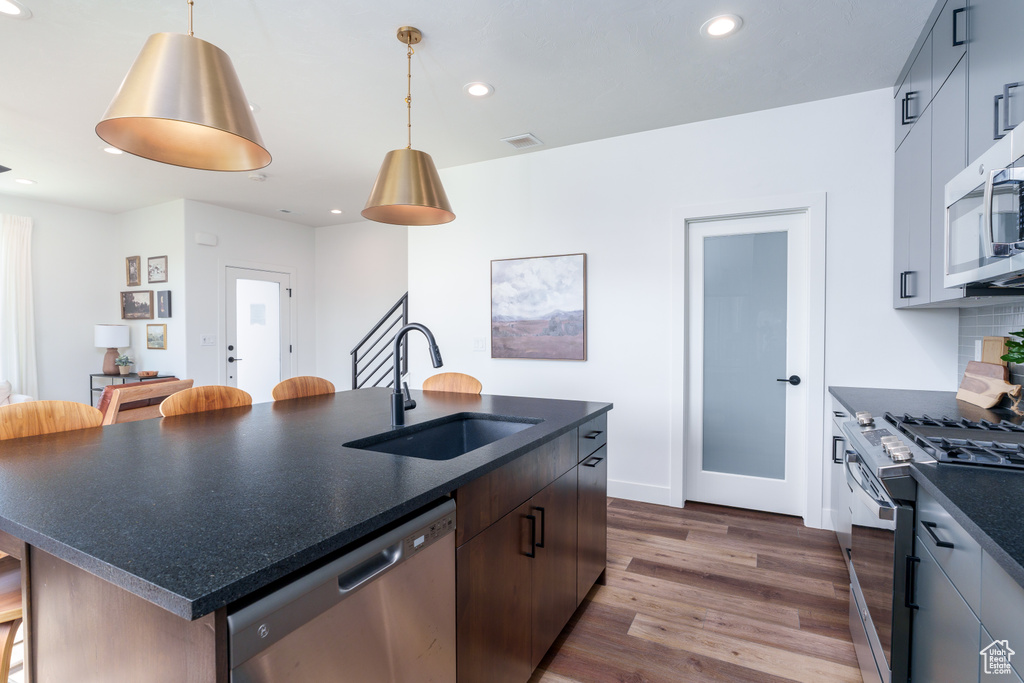 Kitchen with sink, dark hardwood / wood-style flooring, stainless steel appliances, and a center island with sink