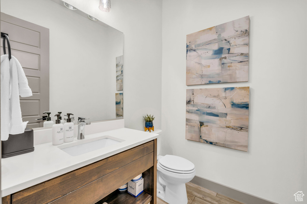 Bathroom featuring hardwood / wood-style flooring, vanity, and toilet
