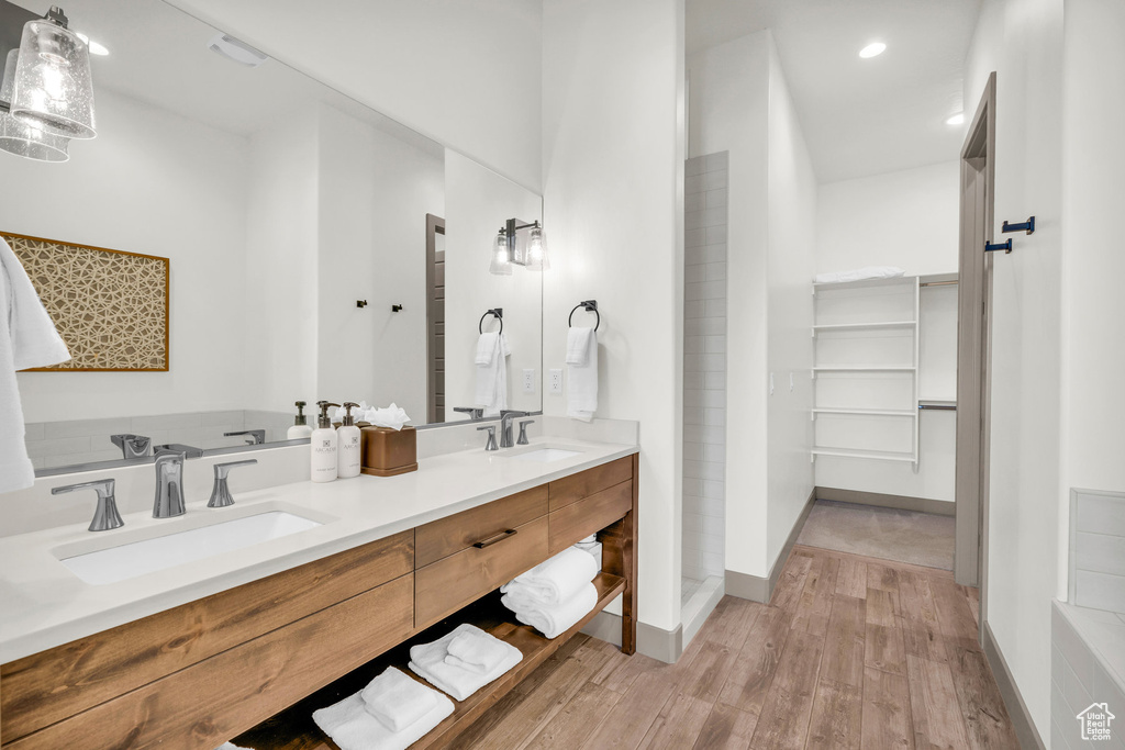 Bathroom with vanity with extensive cabinet space, double sink, hardwood / wood-style floors, and a washtub