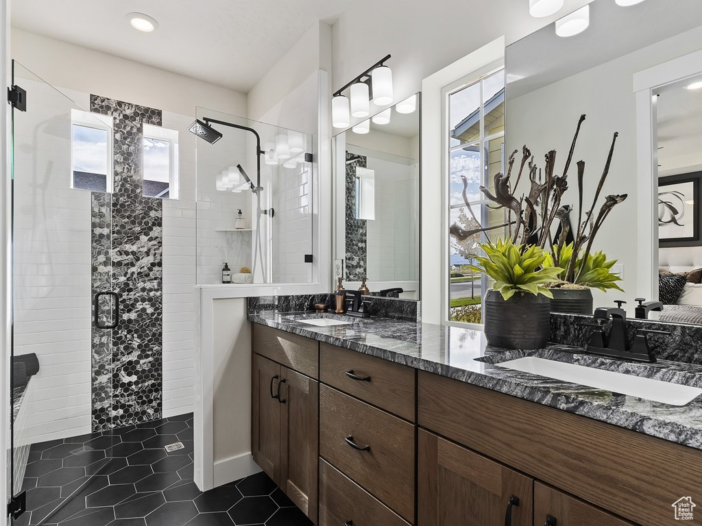 Bathroom with oversized vanity, an enclosed shower, double sink, and tile flooring