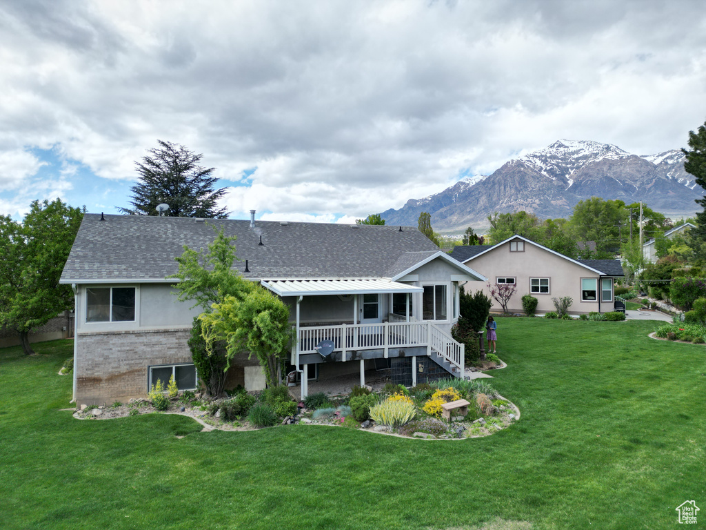 Rear view of property with a mountain view and a lawn