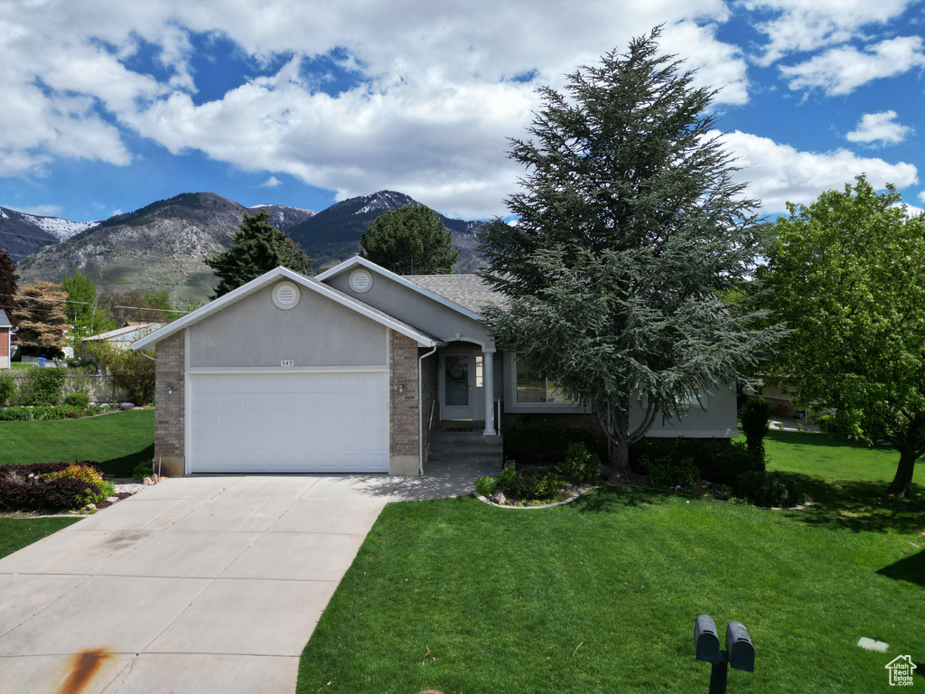 View of front of property featuring a garage, a mountain view, and a front yard