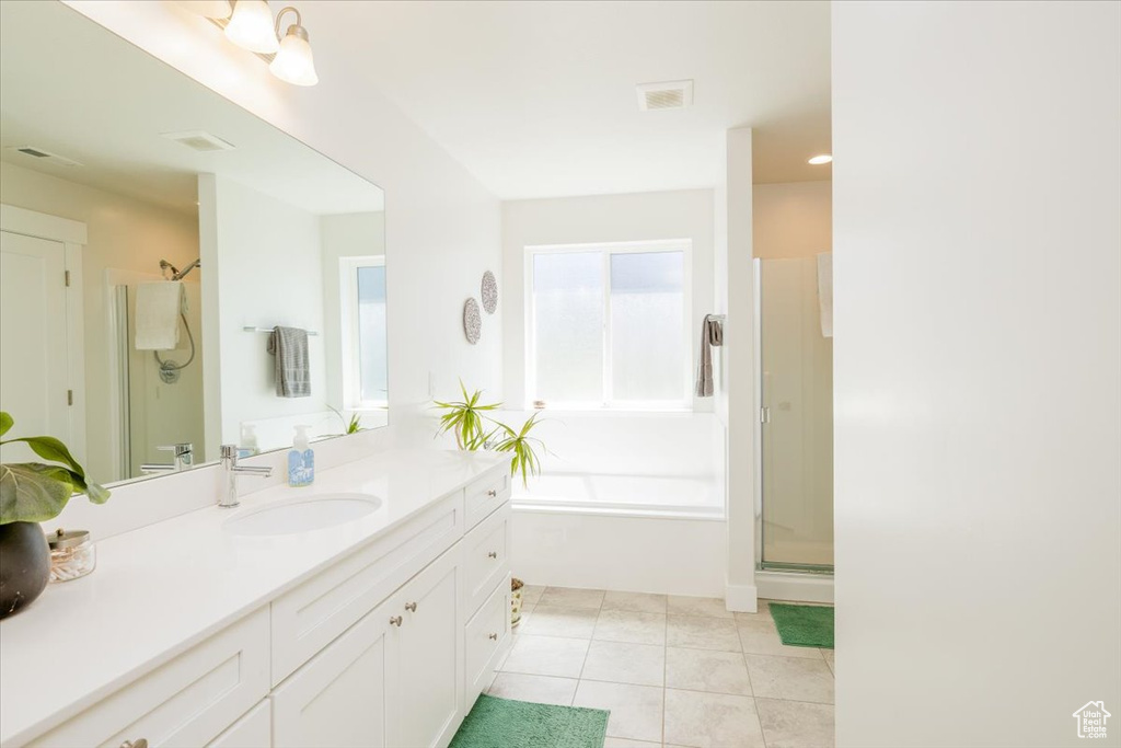 Bathroom featuring a wealth of natural light, independent shower and bath, tile floors, and vanity with extensive cabinet space