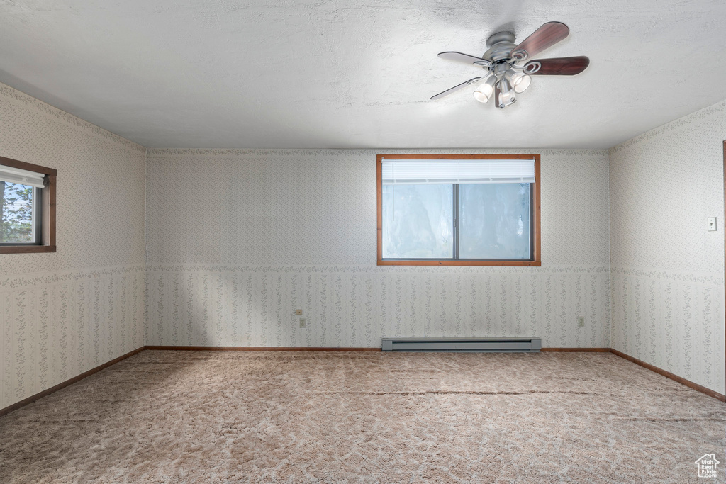 Empty room featuring a baseboard radiator, ceiling fan, and carpet