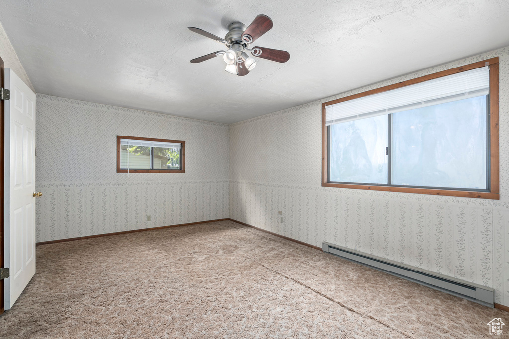 Carpeted empty room with ceiling fan and a baseboard heating unit