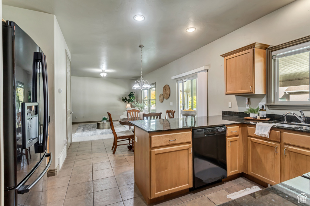 Kitchen with kitchen peninsula, decorative light fixtures, light tile floors, and black appliances