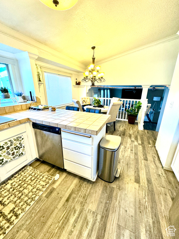 Kitchen with dishwasher, white cabinetry, tile countertops, ornamental molding, and hardwood / wood-style flooring