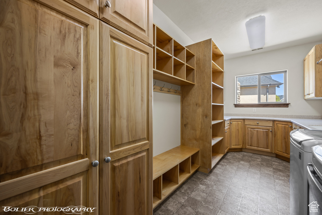 Spacious closet featuring dark tile floors and washing machine and clothes dryer