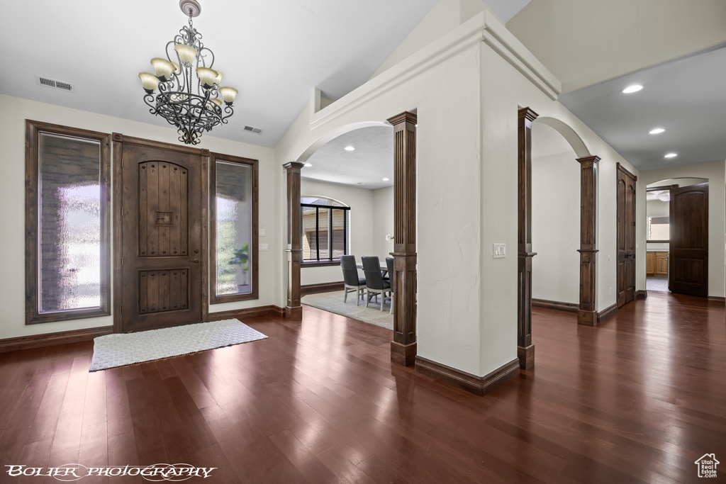 Entryway with an inviting chandelier, dark hardwood / wood-style flooring, and ornate columns