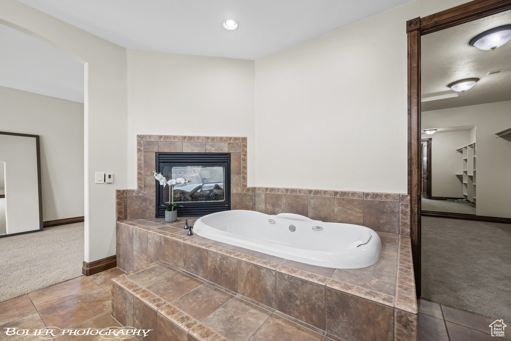 Bathroom featuring tile flooring, a fireplace, and tiled bath