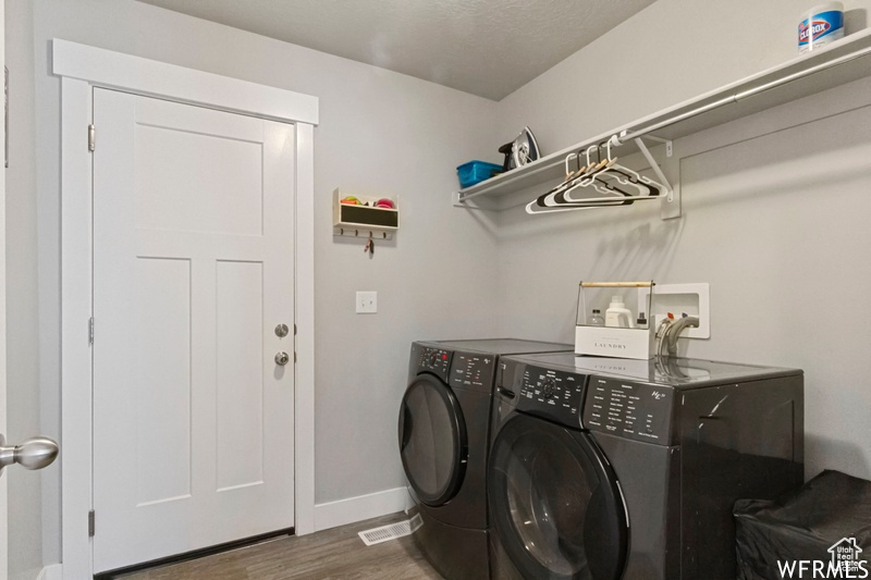 Clothes washing area featuring hookup for a washing machine, dark hardwood / wood-style floors, and washing machine and clothes dryer