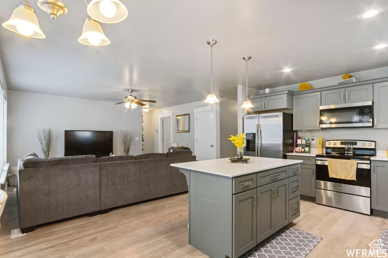 Kitchen with a center island, hanging light fixtures, stainless steel appliances, and light wood-type flooring