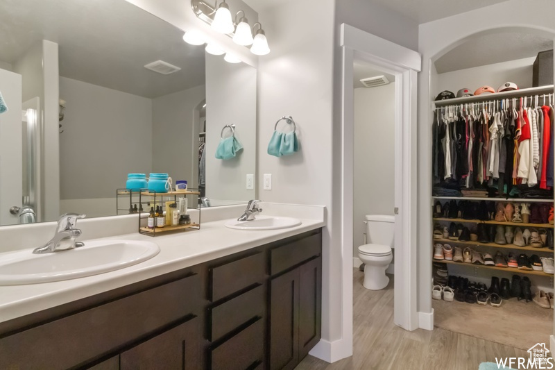 Bathroom with dual sinks, toilet, oversized vanity, and hardwood / wood-style floors