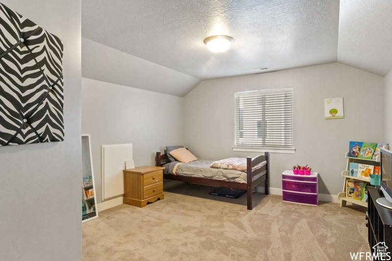 Bedroom with carpet, a textured ceiling, and lofted ceiling