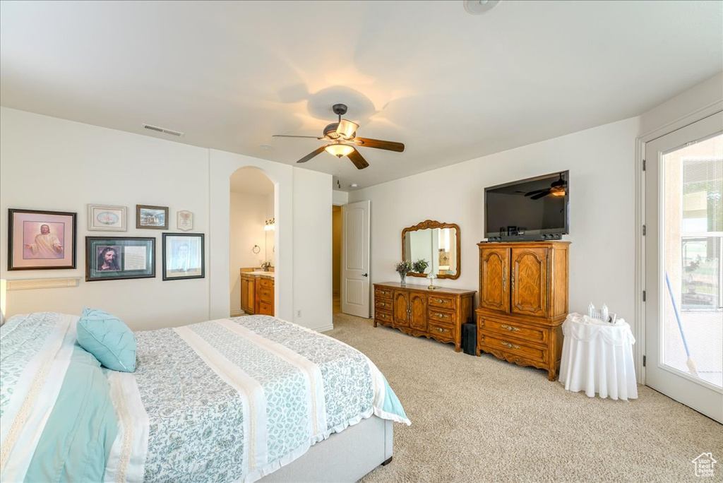 Carpeted bedroom featuring ensuite bath, ceiling fan, and access to outside