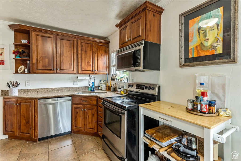 Kitchen with stainless steel appliances, sink, and light tile flooring