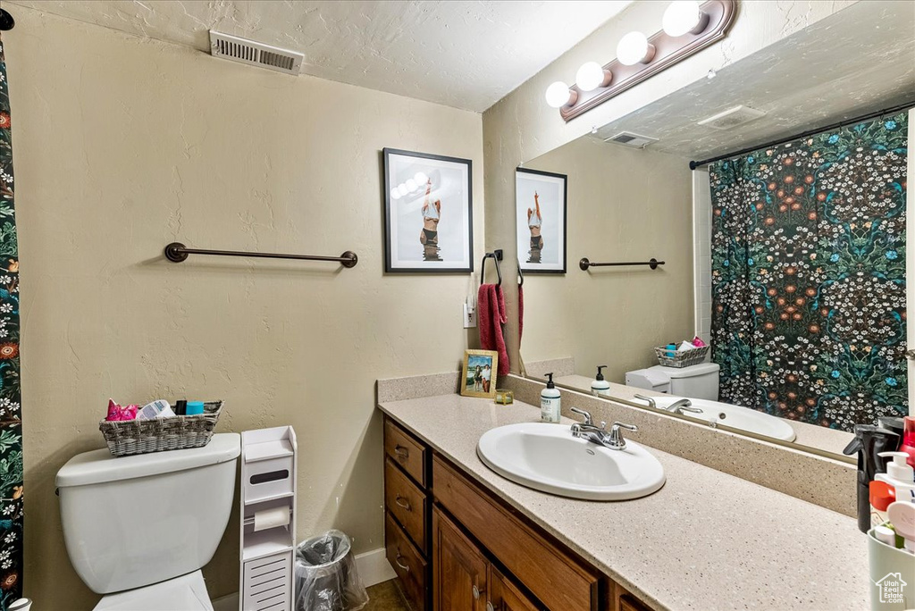 Bathroom with toilet, a textured ceiling, and large vanity