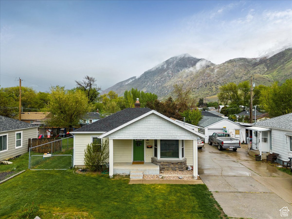 Bungalow-style home featuring a mountain view, a garage, a front lawn, and covered porch