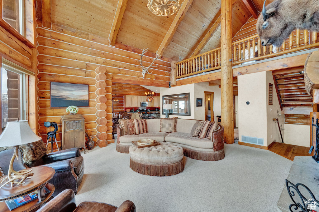 Living room with high vaulted ceiling, log walls, carpet, and wood ceiling