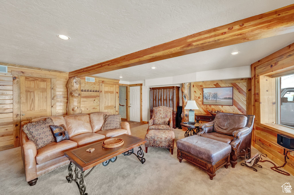 Living room featuring light colored carpet, beam ceiling, wood walls, and a textured ceiling