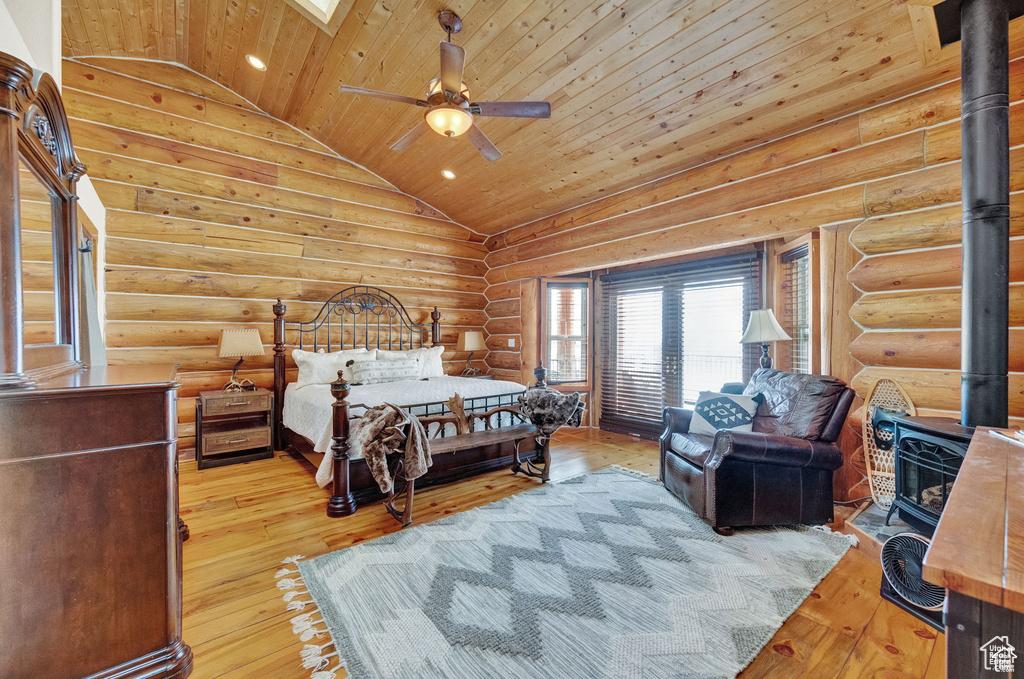 Bedroom featuring wood ceiling, a wood stove, light hardwood / wood-style flooring, and vaulted ceiling