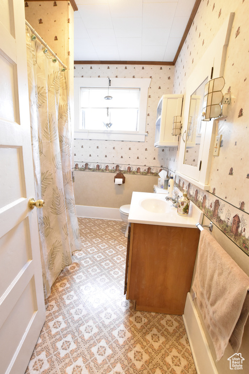 Bathroom with large vanity, tile floors, toilet, and ornamental molding