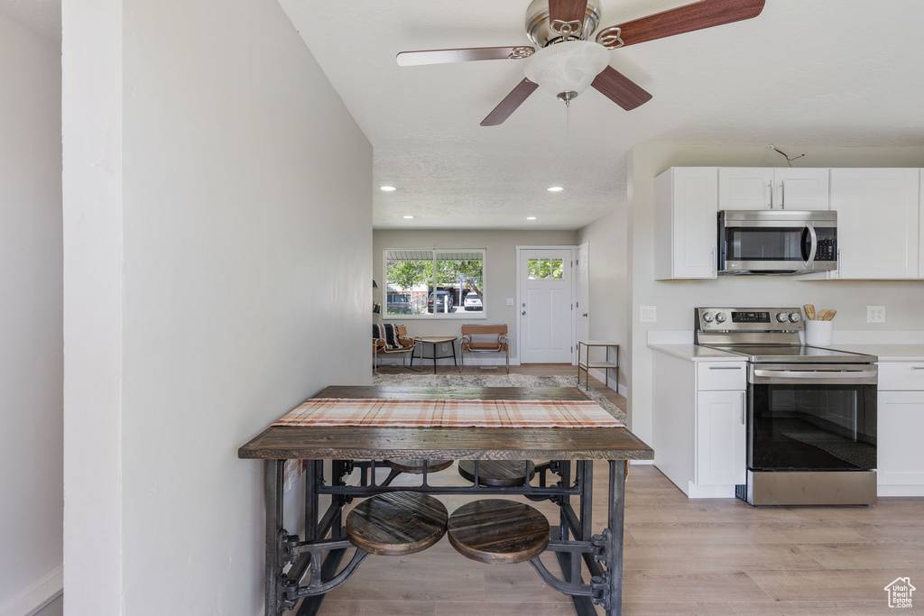 Kitchen featuring light hardwood / wood-style flooring, ceiling fan, stainless steel appliances, and white cabinetry